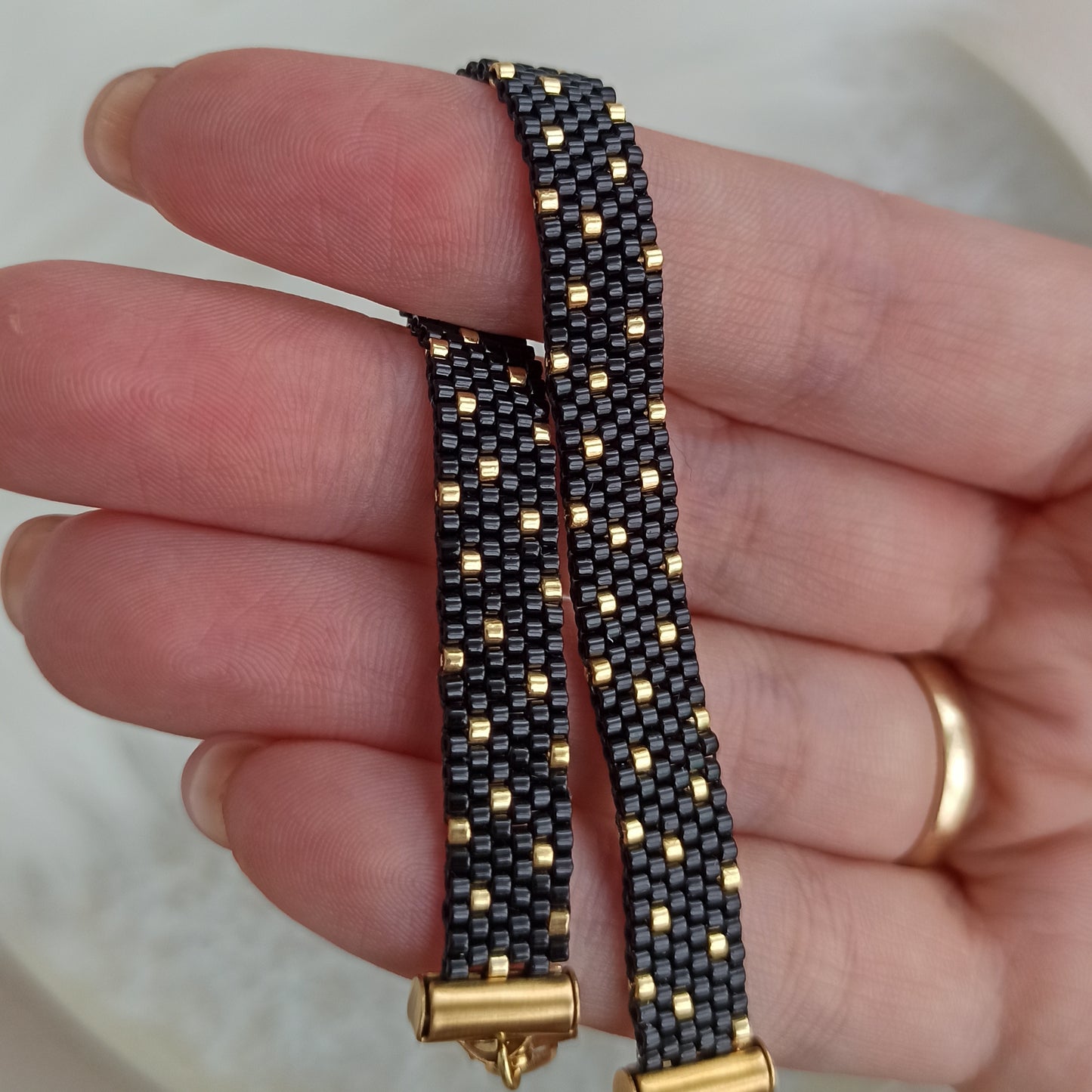 Černý náramek se zlatými tečkami. Na zápěstí 15,5-16,5 cm.