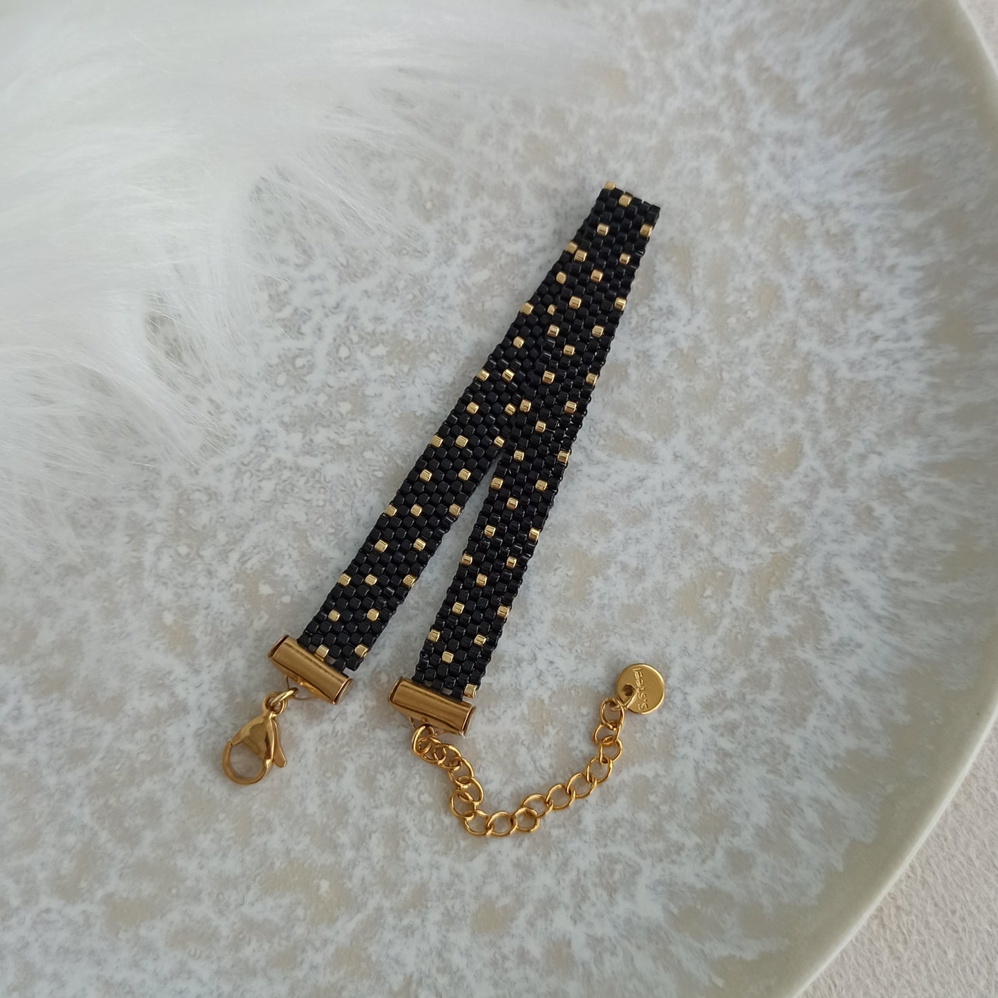 Černý náramek se zlatými tečkami. Na zápěstí 15,5-16,5 cm.